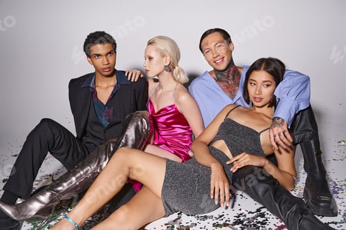 Preview: group of happy multicultural friends sitting near shiny confetti after party, Happy New Year, 2024