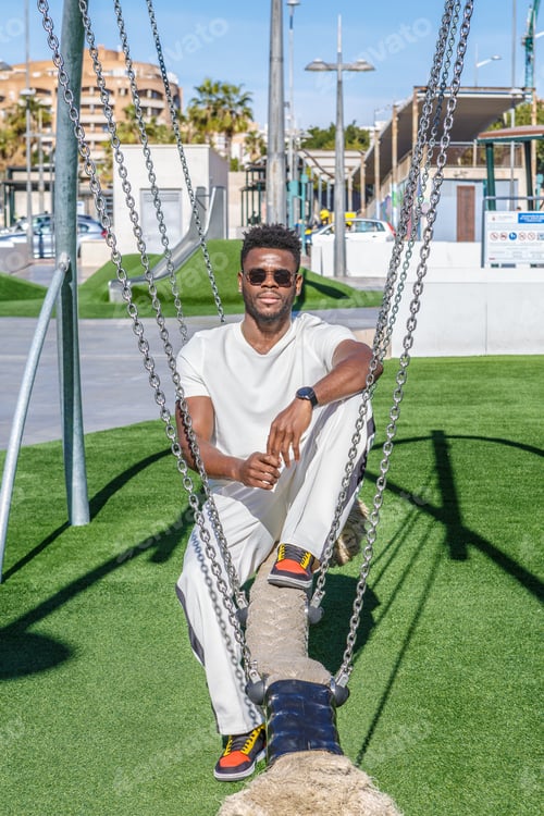 Preview: African American Man Sitting on a Swing in a Public Park