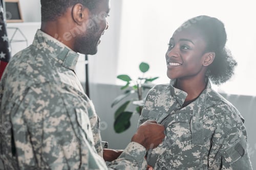 Preview: Male soldier helping woman to get dressed in camouflage clothes