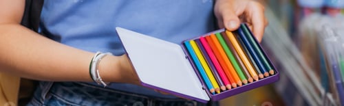 Preview: cropped view of woman in beaded bracelets holding box of color pencils, banner