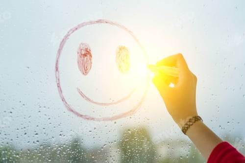 Preview: Hand draws positive funny smiley on a rainy autumn window