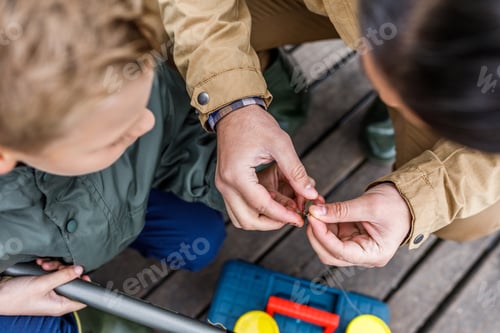 Preview: father and son fishing together on wooden pier
