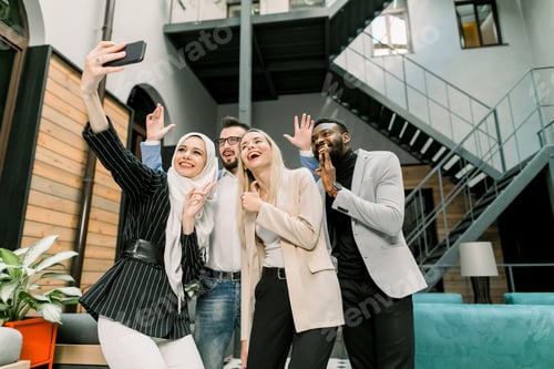 Preview: Happy smiling four young multiethnic business colleagues making selfie photo together, smiling, and