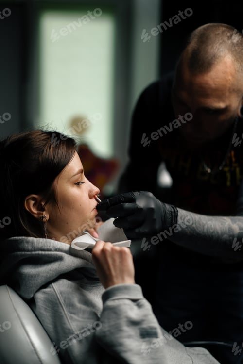 Preview: Piercing process Professional nose piercing for a girl the master pierces the nose with needle