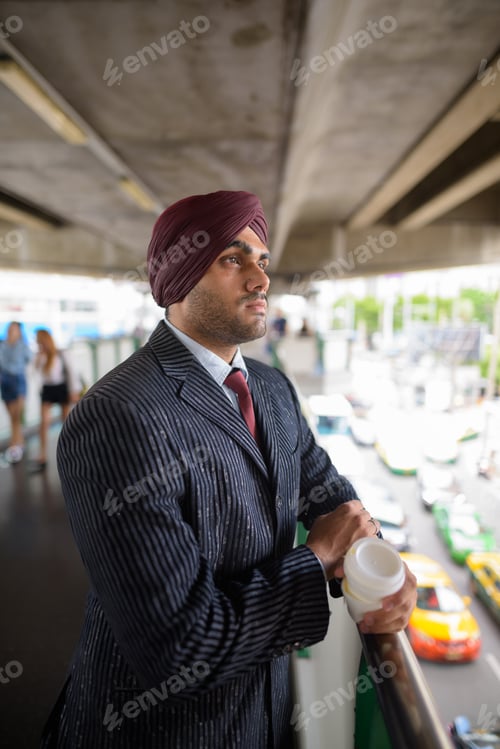 Preview: Young handsome Indian Sikh businessman wearing turban outdoors in city