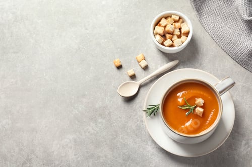Preview: Flat lay composition with mug of tasty sweet potato soup and space for text on grey background