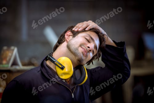 Preview: Portrait industry worker wearing uniform and ear phone relaxing at his work desk in office at break