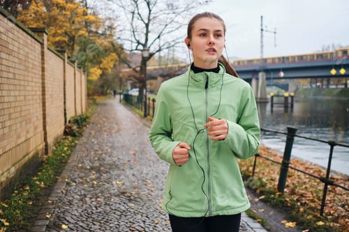 Preview: Beautiful sporty girl in earphones running with music around park