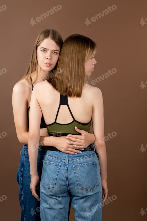Preview: Attractive blond teenage girl embracing her twin sister