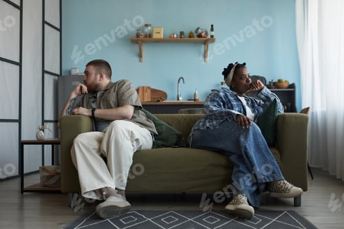 Preview: Young Caucasian Man and Young Black Woman Sitting Apart Experiencing Conflict