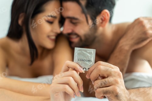 Preview: Close up of Caucasian young man and Asian woman holding condom together.