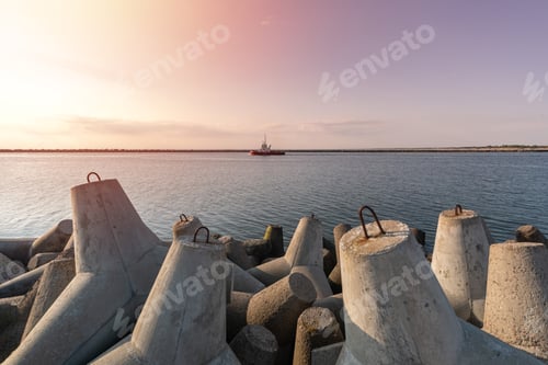 Preview: Tugboat sailing in sea to tow ship to port. Tetrapod breakwaters in harbor