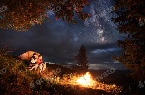 Preview: Tent city at night and pair sitting by fire looking into the distance under the evening sky
