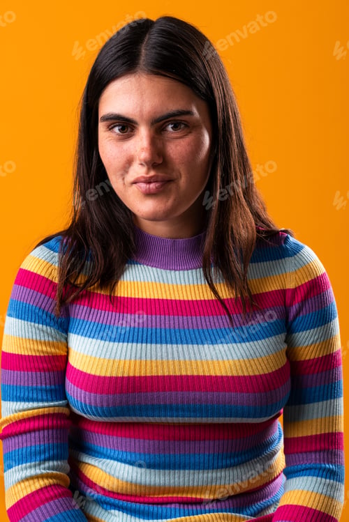 Preview: Young woman with colorful striped sweater posing on orange background