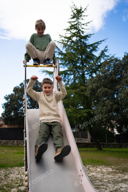 Preview: Children having fun on slide in playground on sunny day