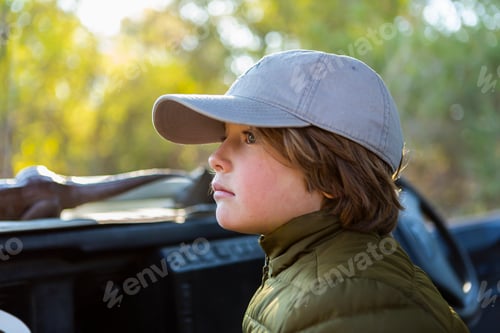 Preview: Portrait of young boy in a baseball cap in a safari vehicle.