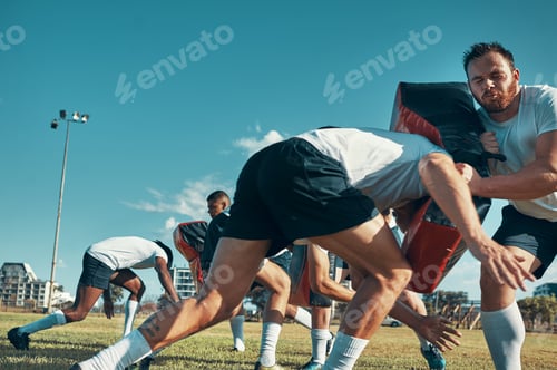 Preview: Shot of a group of rugby players training with tackle bags on the field