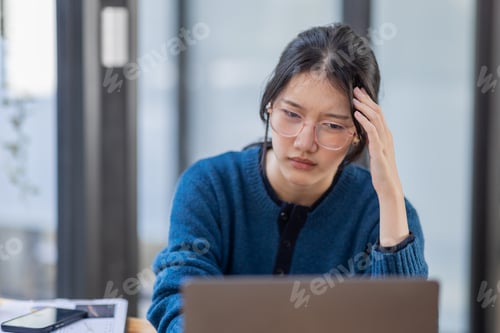 Preview: Portrait of tired young business Asian woman work with documents tax laptop computer in office. Sad,