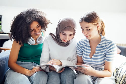 Preview: Three pretty female teenagers of different nationalities are reading a magazine and smiling