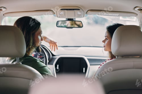 Preview: Young couple enjoying a conversation in a car interior, facing each other with attention, creating