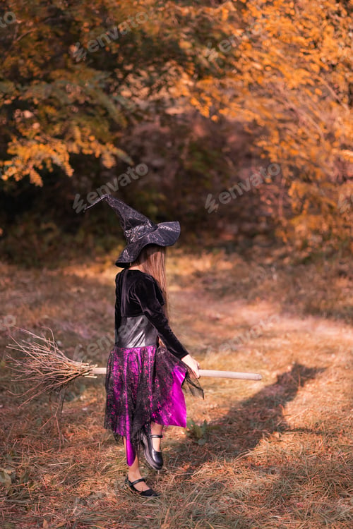 Preview: 8-year-old girl in witch costume in nature in autumn forest sitting on meter shadow witch
