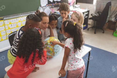 Preview: High angle view of a teacher and school kids interacting about a earth globe in classroom