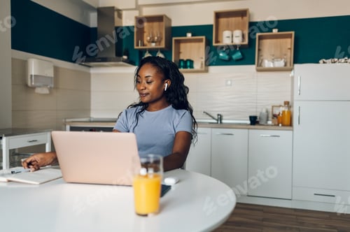 Preview: Young african american woman working from home and using a laptop
