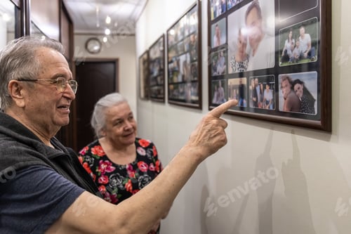 Preview: Grandparents look at family photographs on the wall.