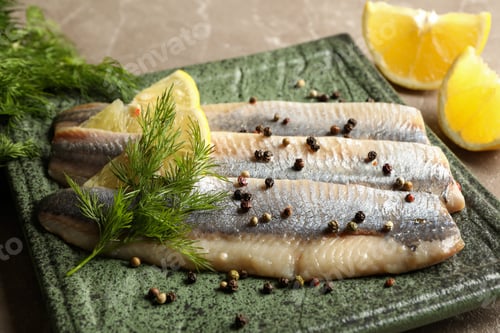 Preview: Plate with herring fish slices and spices on gray background