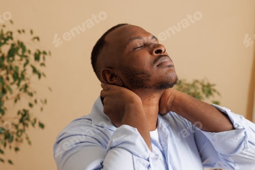 Preview: Close-up of a man experiencing neck pain, holding the back of his neck with both hands