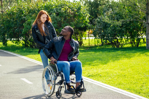 Preview: afro american man sitting on wheelchair ,his redhaired ginger girlfriend