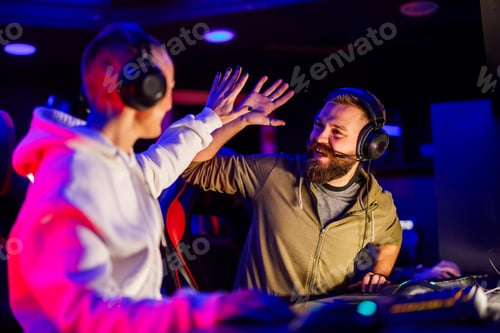 Preview: Cybergame players giving high five and celebrating victory in cybercafe