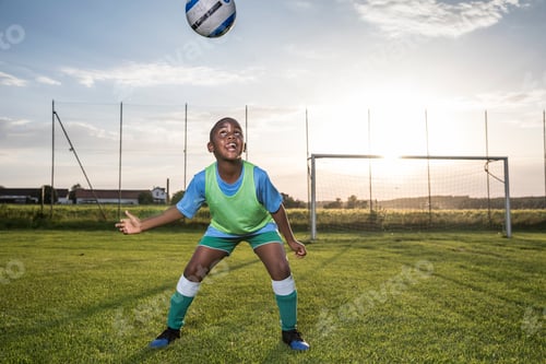 Preview: Young football player heading the ball on football ground