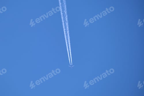 Preview: Distant passenger jet plane flying on high altitude on clear blue sky leaving white smoke trace of