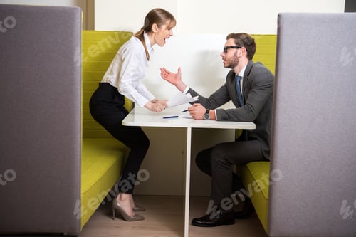 Preview: Business colleagues arguing while sitting at table with papers and pens