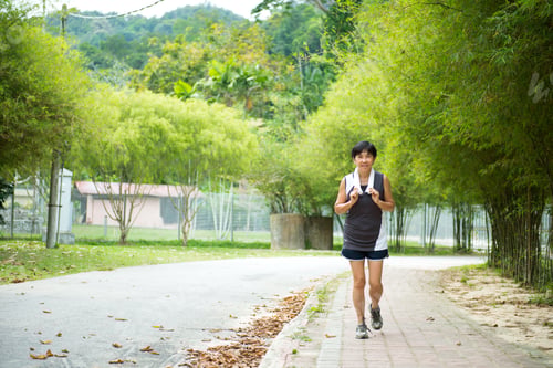 Preview: Front view of senior woman jogging through park