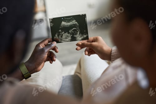Preview: Close up of man and woman holding baby ultrasound picture