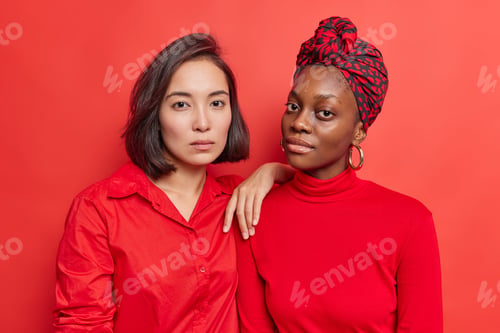 Preview: Portrait of serious multiethnic women stand closely to each other have calm confident look at camera