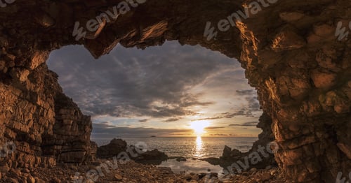 Preview: Beautiful seascape through the rocks on the cloudy sky background at sunset