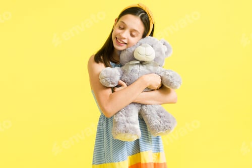 Preview: Little girl having fun while embracing a teddy bear