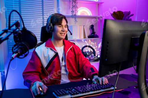 Preview: Asian young esport male gamer playing online video game on computer.