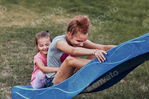 Preview: Teenage girl playing with her younger sister in a home playground in a backyard
