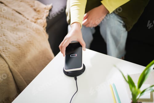 Preview: Charging mobile phone battery with wireless charging device in the table. Smartphone