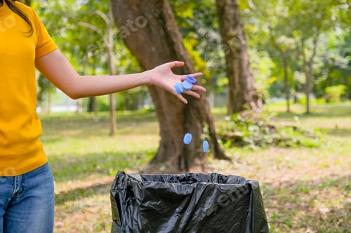 Preview: Hand of yellow t-shirt woman hold lot of bottle caps in the park or garden.
