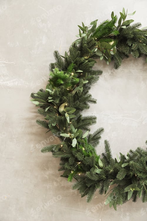 Preview: Christmas wreath made of fir branches hanging on a gray wall. Half wreath