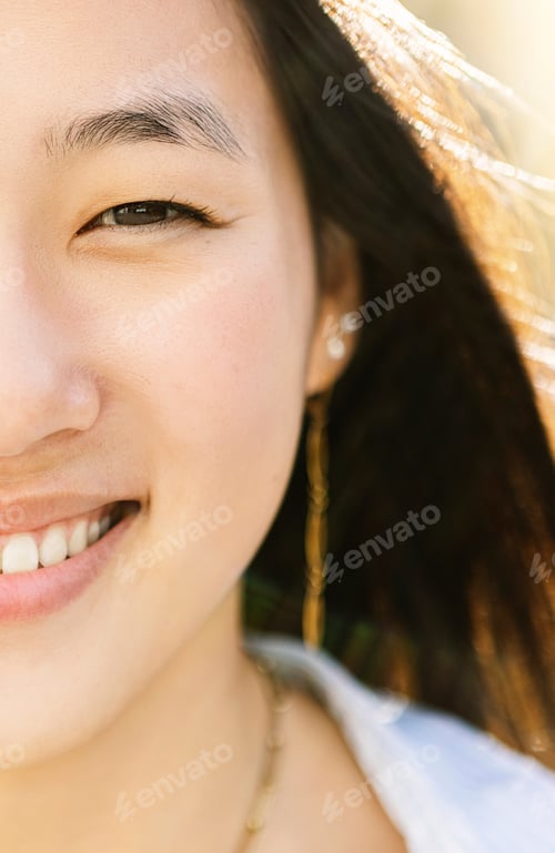 Preview: Closeup front portrait of happy young asian woman smiling at camera outdoors