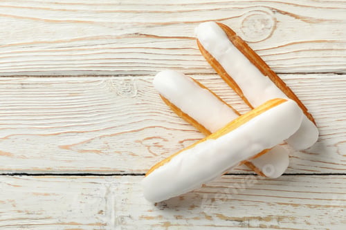 Preview: Tasty eclairs with custard on wooden background