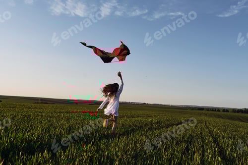 Preview: With red colored kite. Happy girl have a walk outdoors on the field at summer