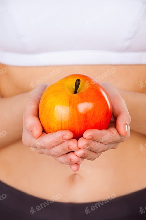 Preview: Be healthy. Close up of woman in sports clothing holding apple