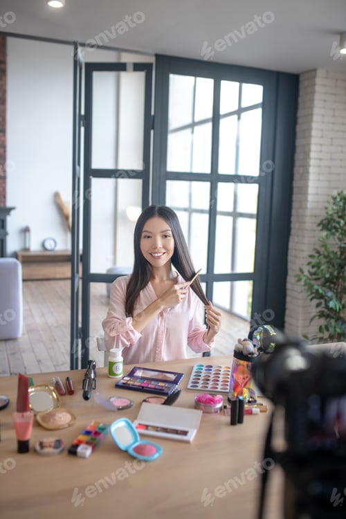 Preview: Beauty blogger brushing hair while filming video about hair daily procedures